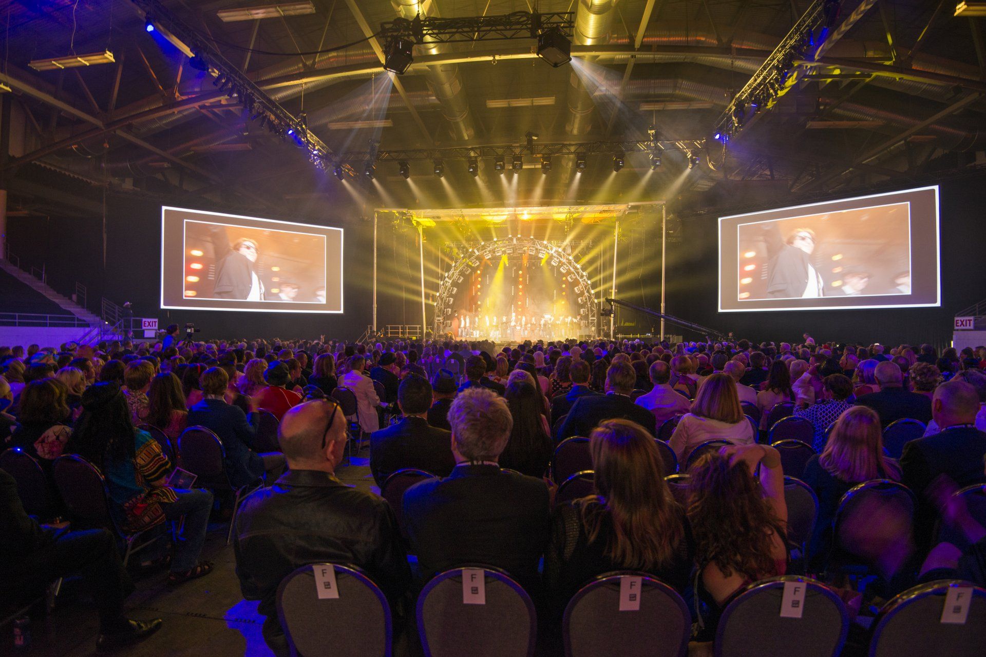 A large crowd of people are sitting in front of a stage at a concert.