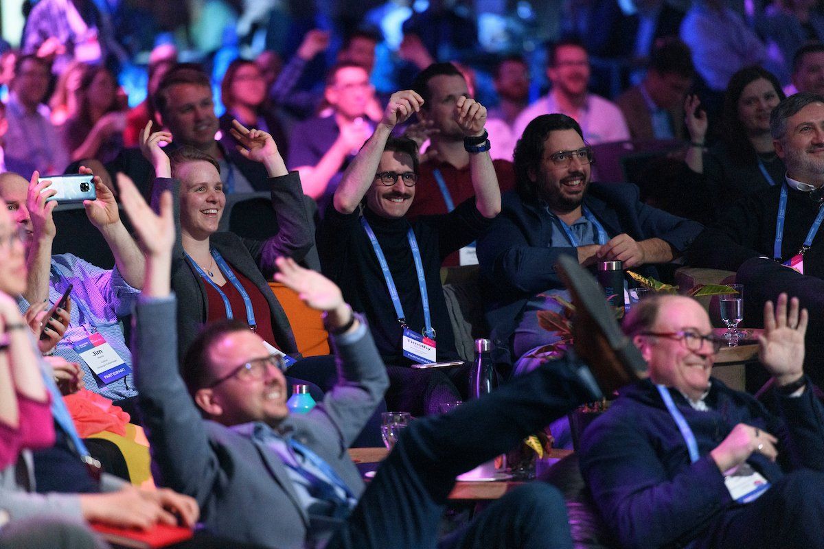A group of people are sitting in a stadium with their arms in the air.