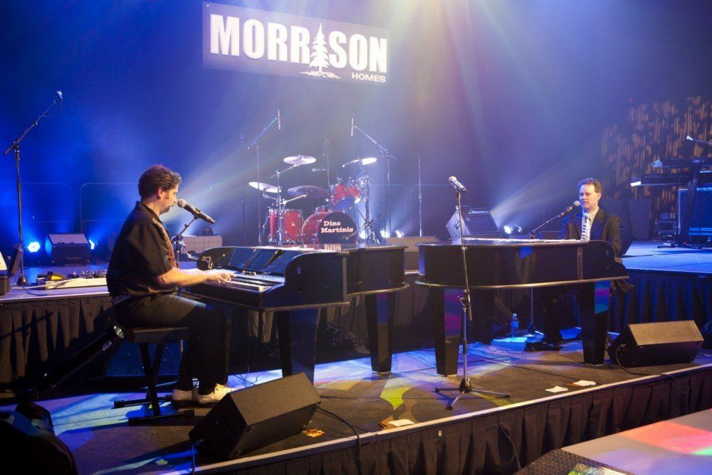 Two men are playing pianos on a stage in front of a sign that says morrison