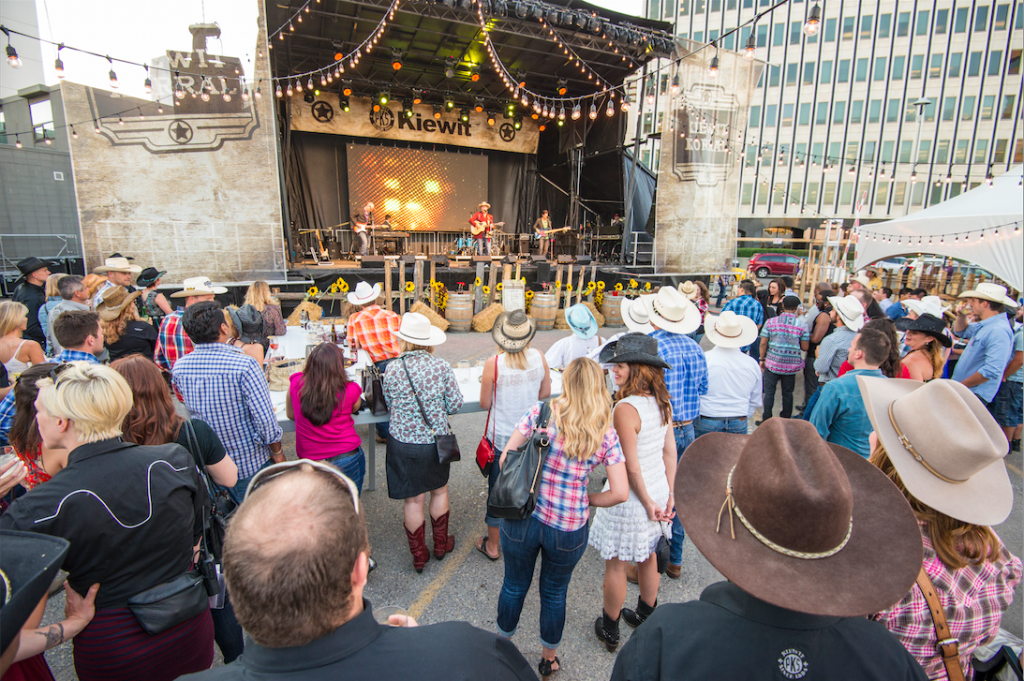 A crowd of people are standing in front of a stage at a country music festival.