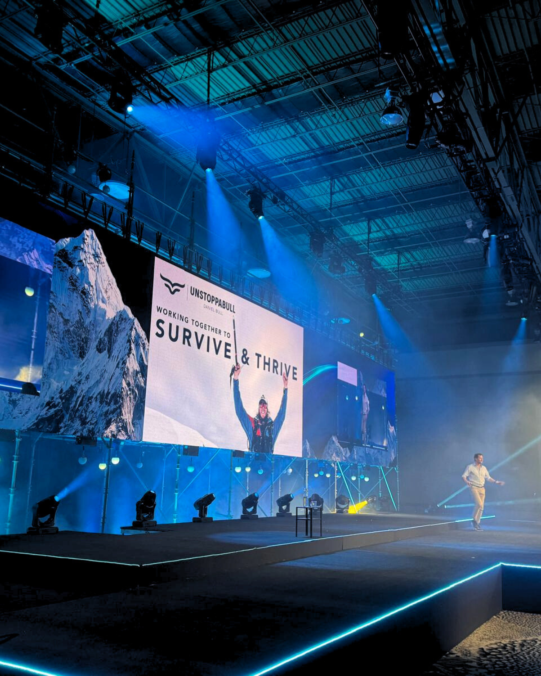 A stage with a large screen that says survive & thrive