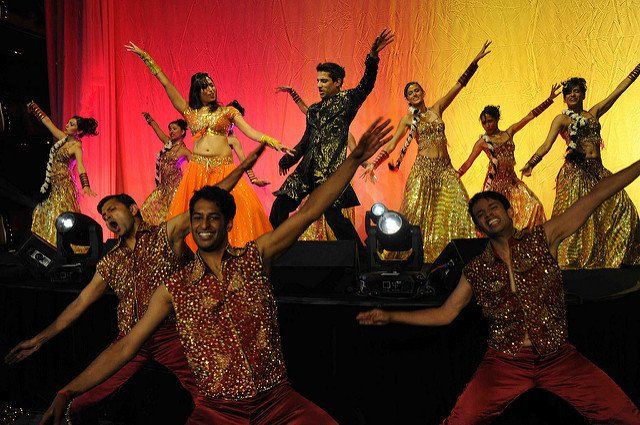 A group of people are dancing on a stage with their arms in the air