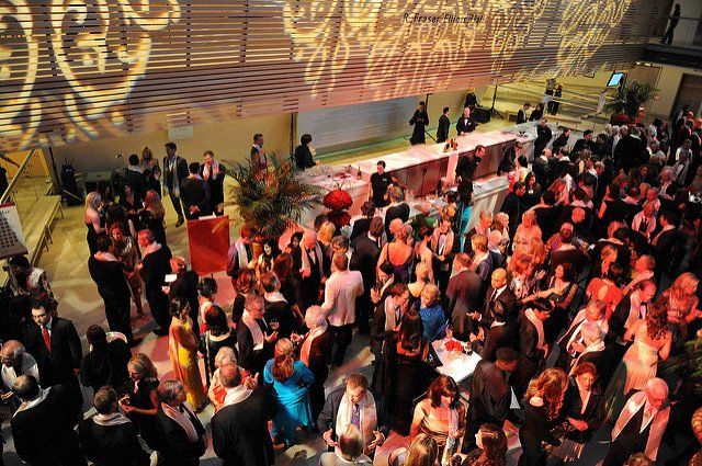 A large group of people are standing in a room at a party.