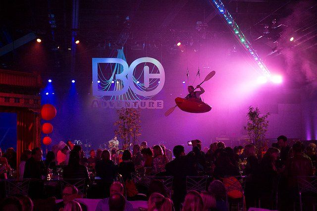 A man in a kayak is flying through the air at a party.