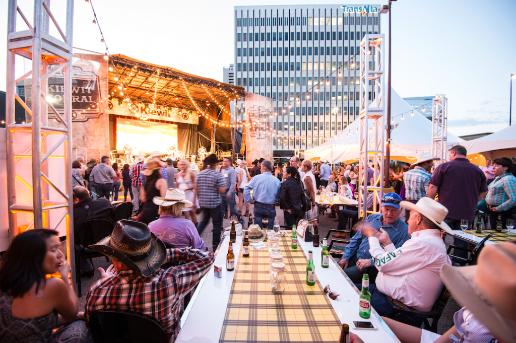 A group of people are sitting around a long table with bottles of beer.