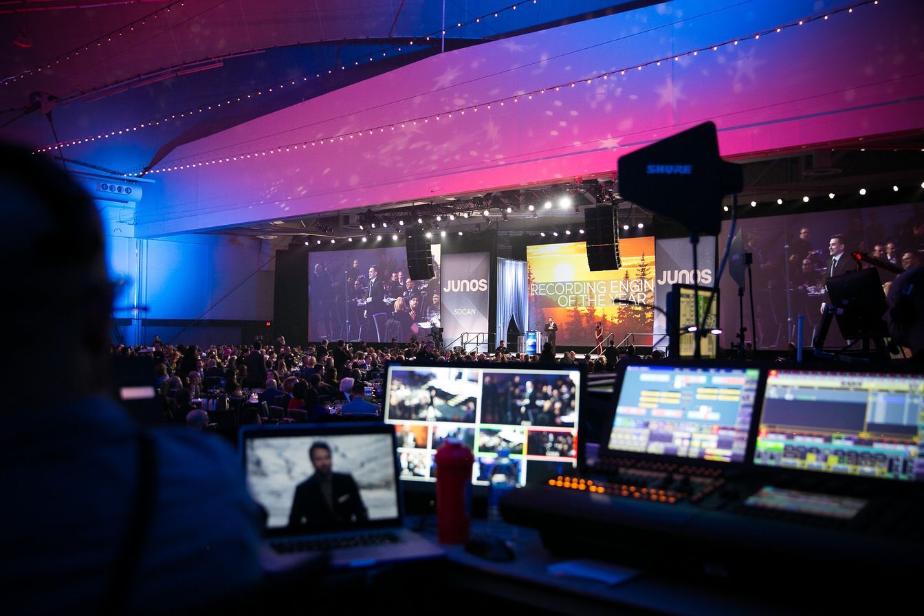A man is sitting in front of a large screen watching a live event.