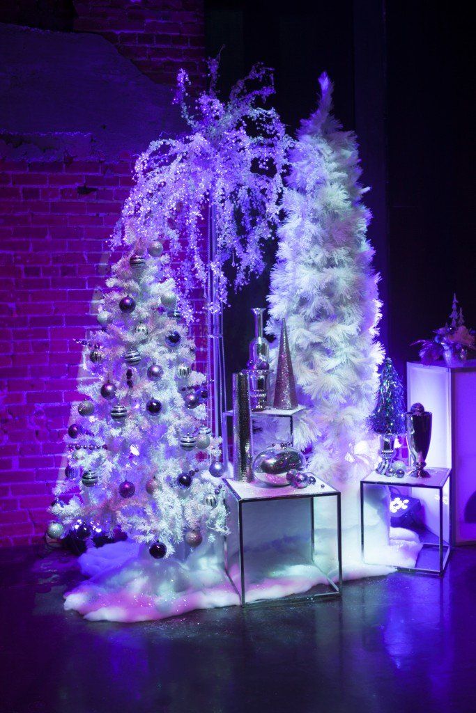 There is a christmas tree in the middle of the room with purple lights.