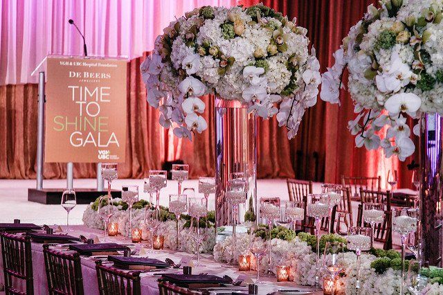 A long table set for a gala with flowers and candles on it.