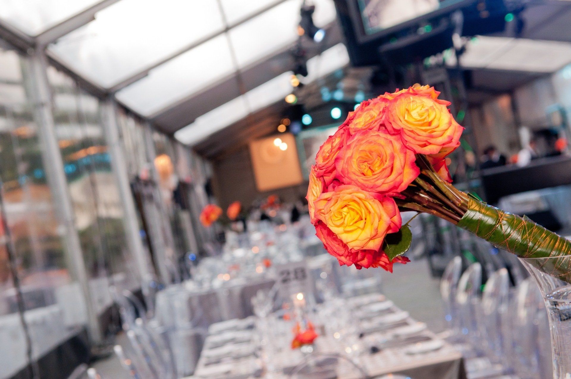 A bouquet of roses is sitting on top of a long table.