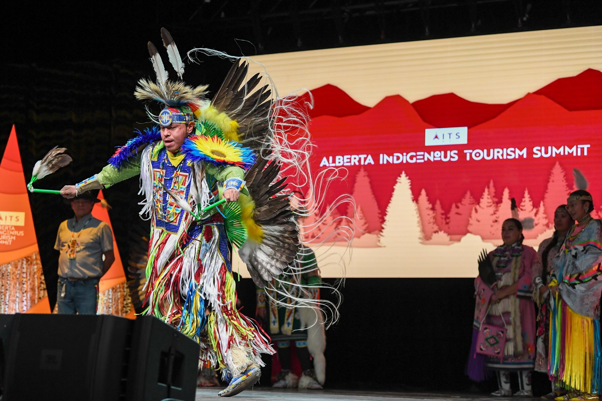 A man in a native american costume is dancing on a stage.