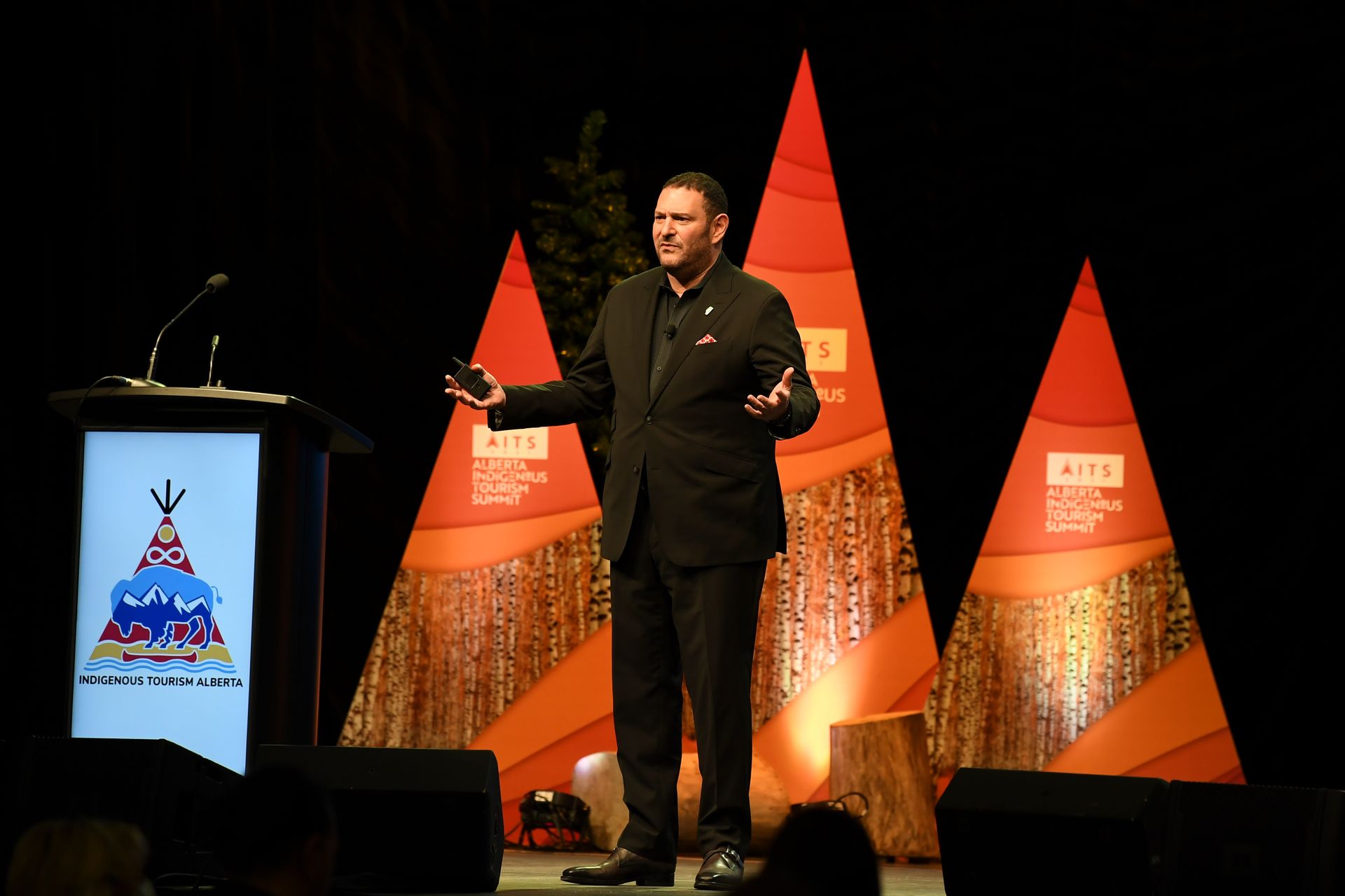 A man in a suit stands at a podium giving a speech