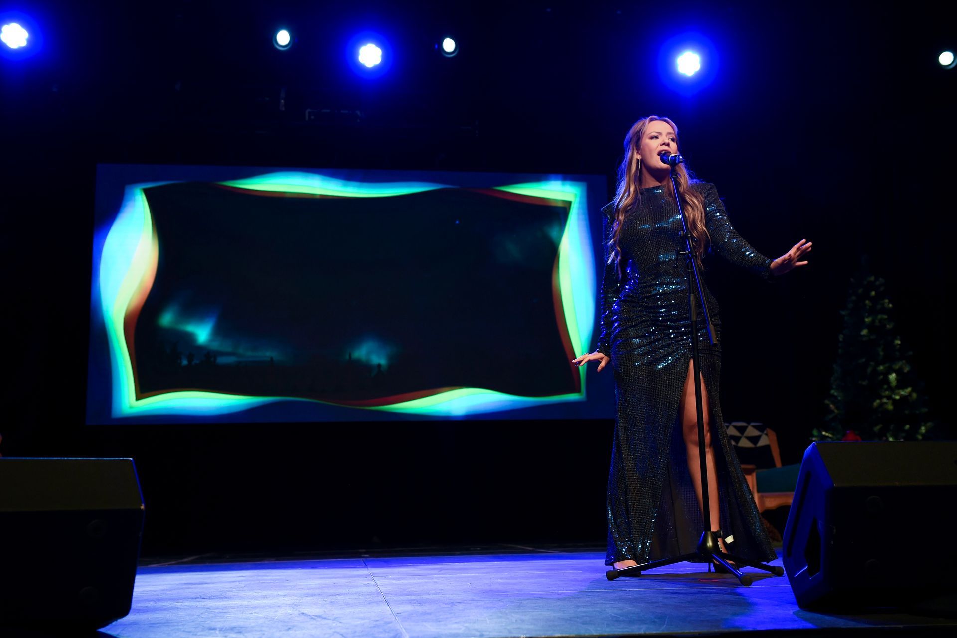 A woman is singing into a microphone on a stage.