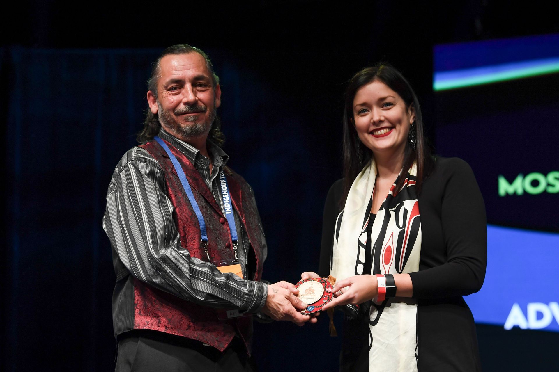 A man and a woman are shaking hands on a stage.