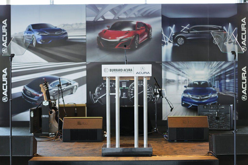 A podium in front of a wall with acura cars on it
