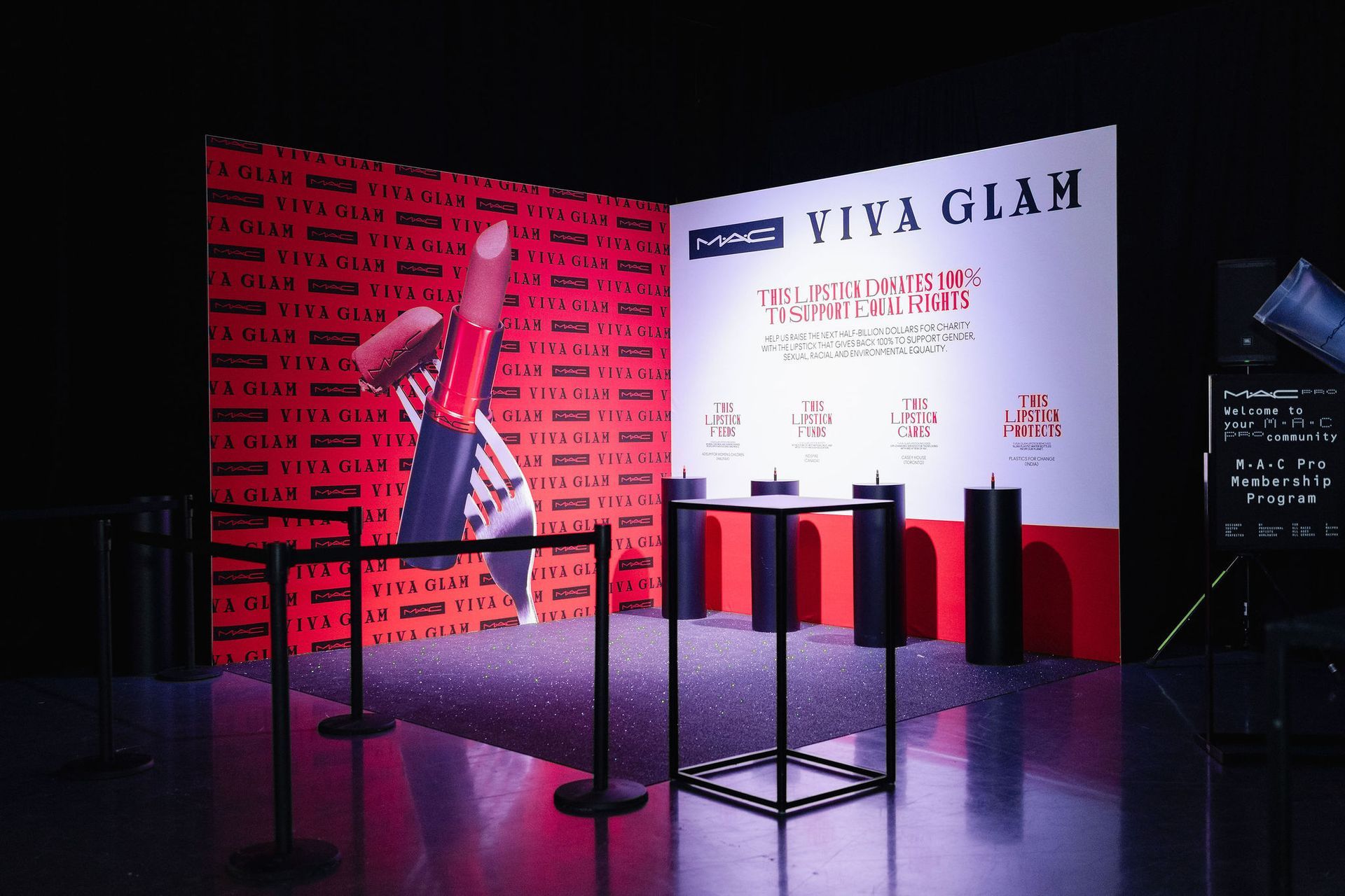 MAC Viva Glam display with lipstick graphic, information panel, and velvet ropes. Red, black, and white colors.