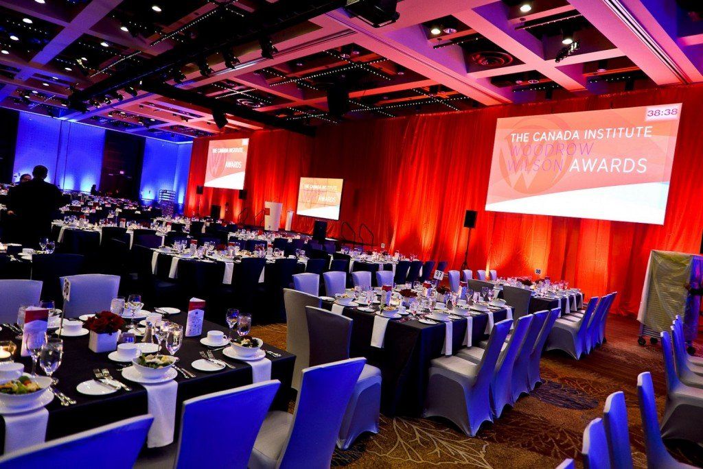 A large room filled with tables and chairs and a large screen that says awards
