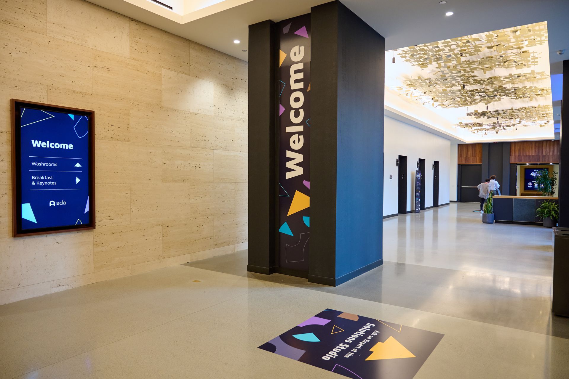 A lobby with a welcome sign on the wall and a welcome mat on the floor.