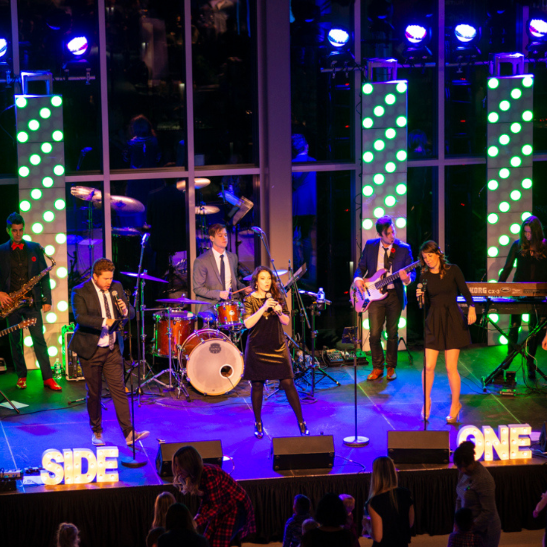 A group of people are standing on a stage playing instruments.