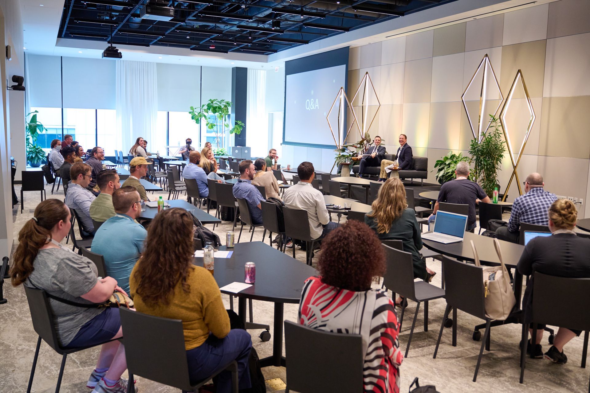 A large group of people are sitting at tables in a conference room.