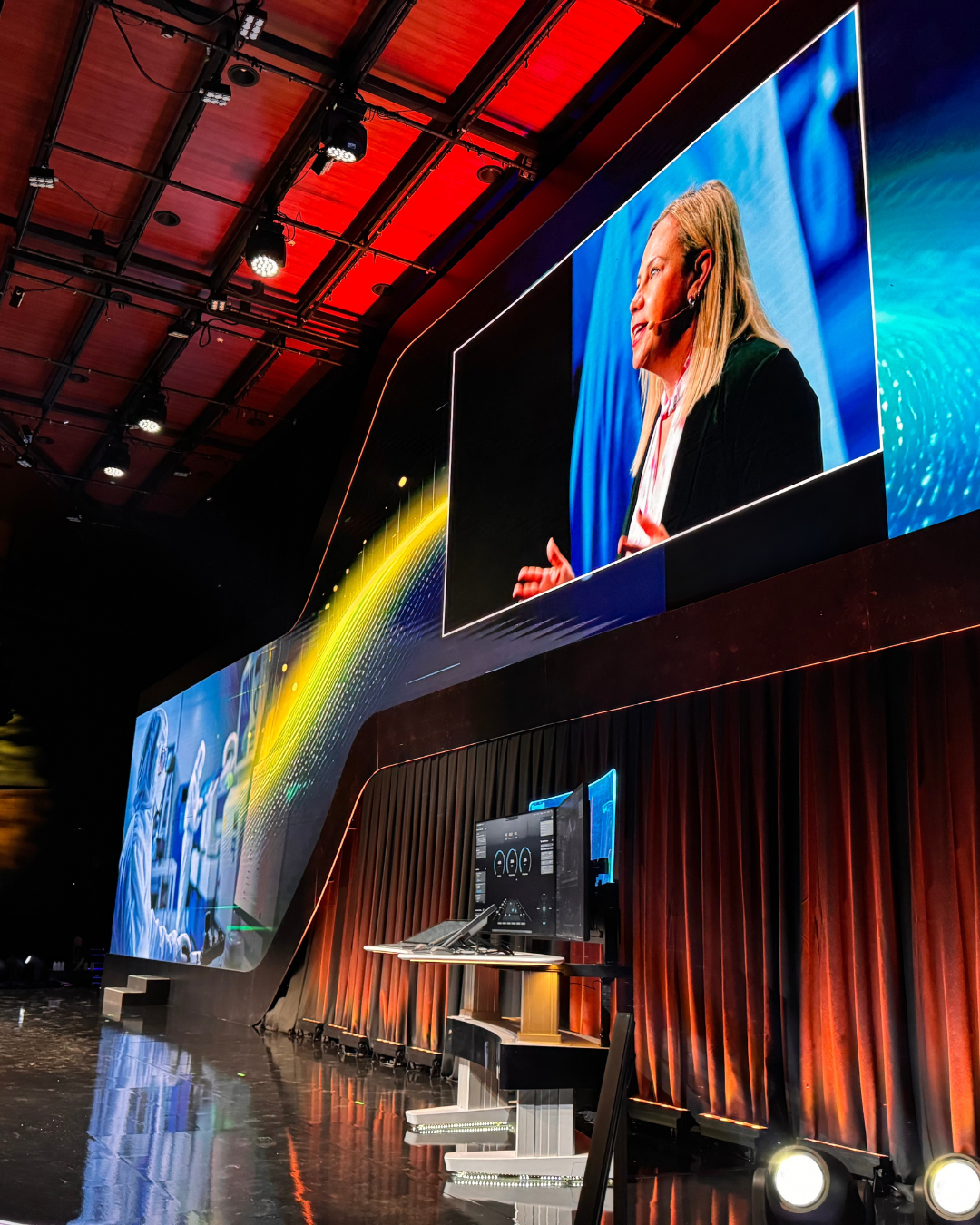 A man is giving a speech in front of a large screen