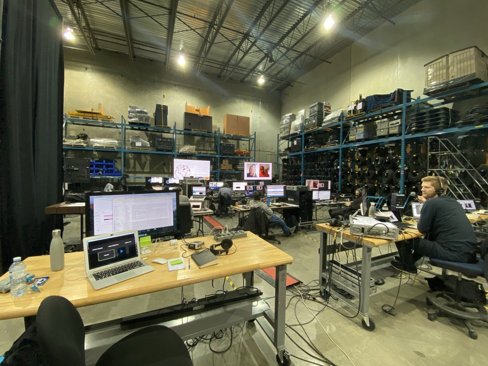 A warehouse filled with lots of computers and people sitting at desks.