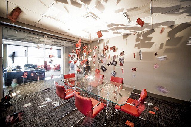 A conference room with a glass table and red chairs