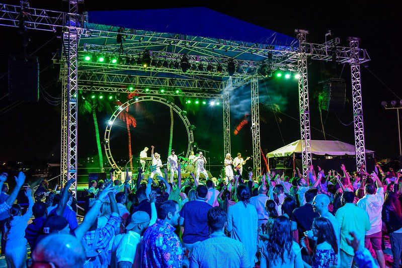 A crowd of people are standing in front of a stage at a concert.