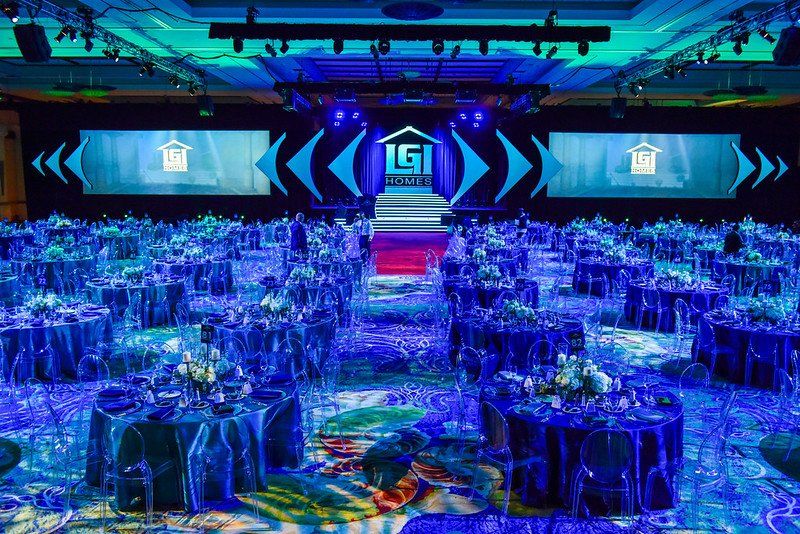 A large room filled with tables and chairs and a stage.