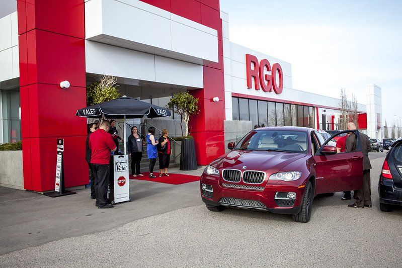 A red car is parked in front of a building that says rgo