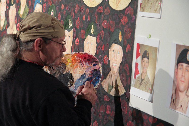 A man is painting a picture of soldiers on a wall.