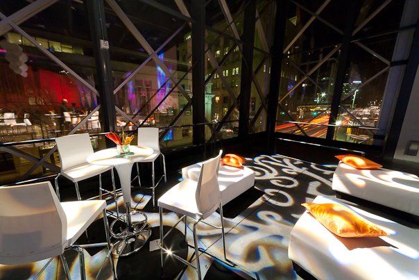 A room with tables and chairs and a rug that says ' s ' on it