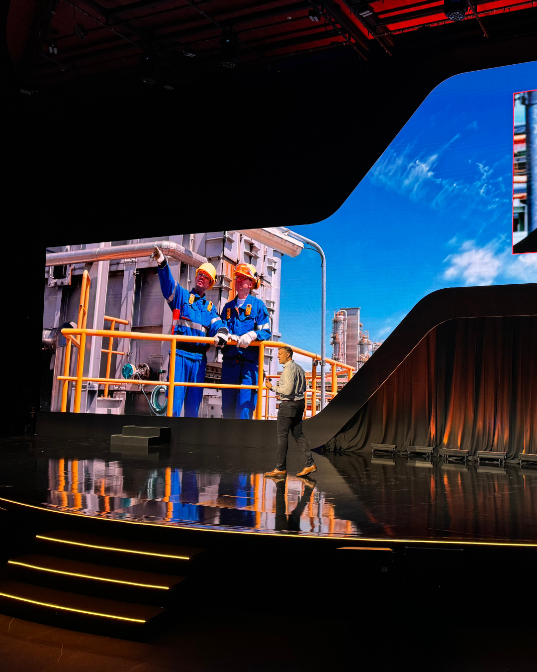 Two men standing on a stage in front of a large screen