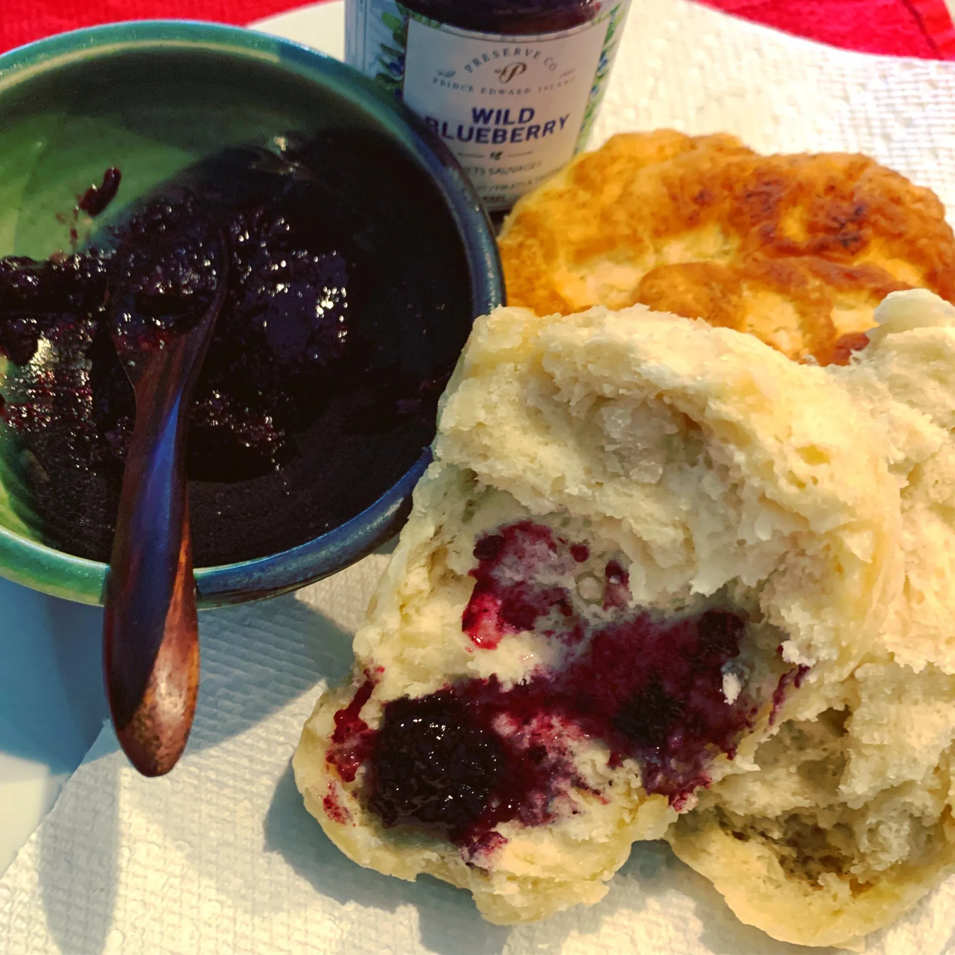 A bowl of wild blueberry jam next to a biscuit