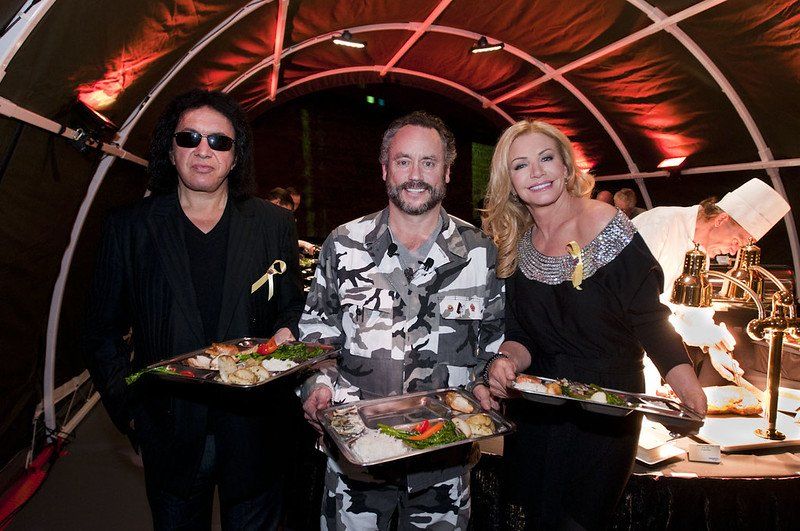 A group of people standing next to each other holding plates of food.