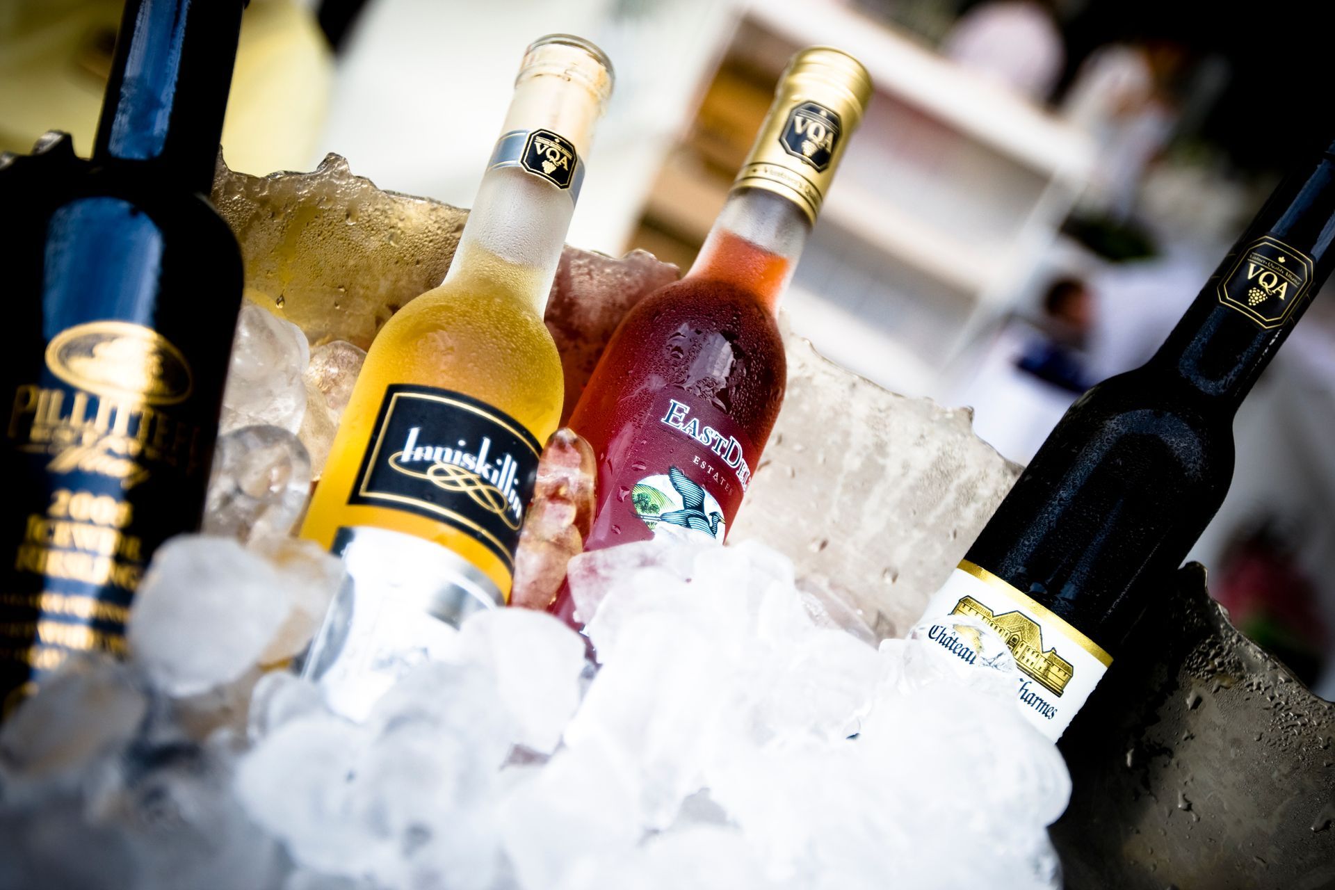 Bottles of wine chilling in ice; varying colors, with labels, outdoors.