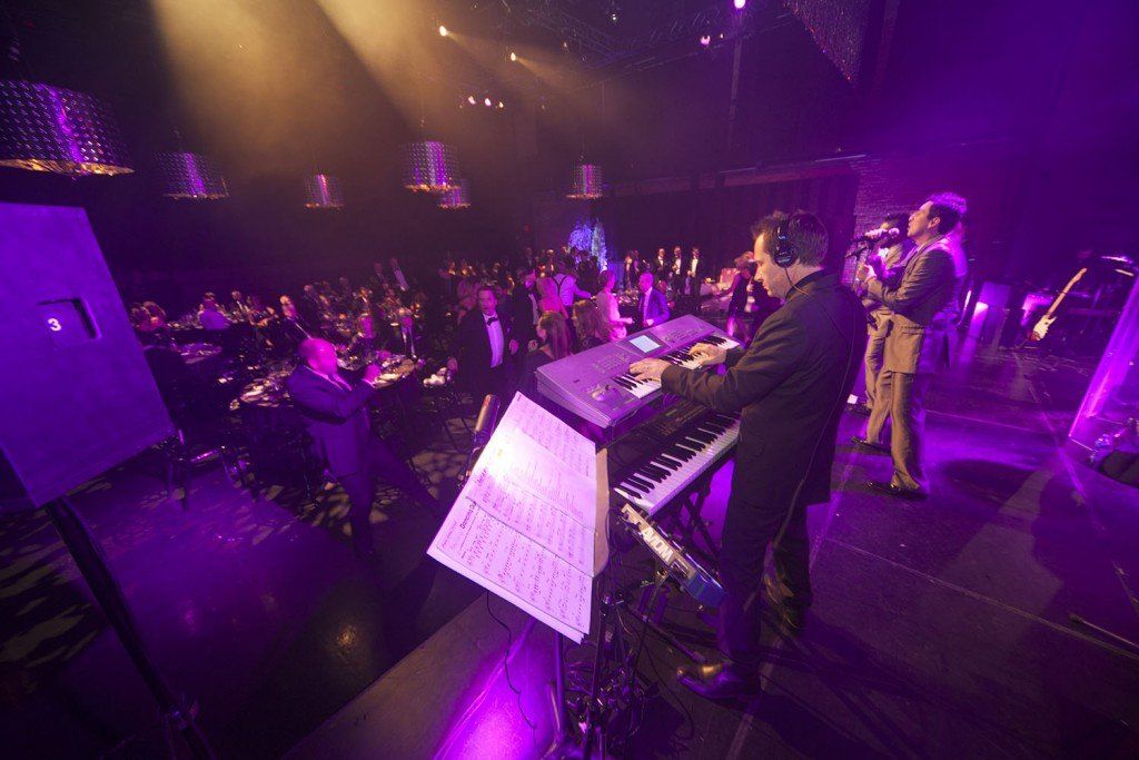 A man is playing a keyboard on a stage in front of a crowd.