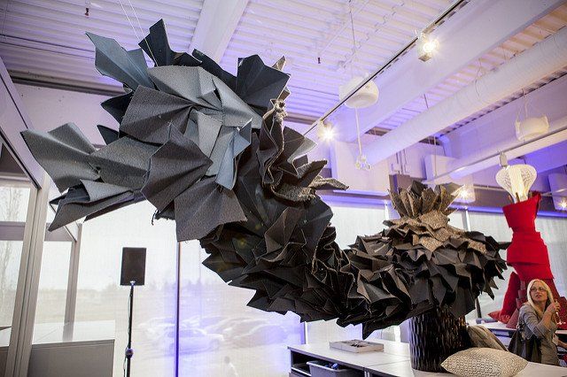 A large sculpture made of paper is hanging from the ceiling in a room.