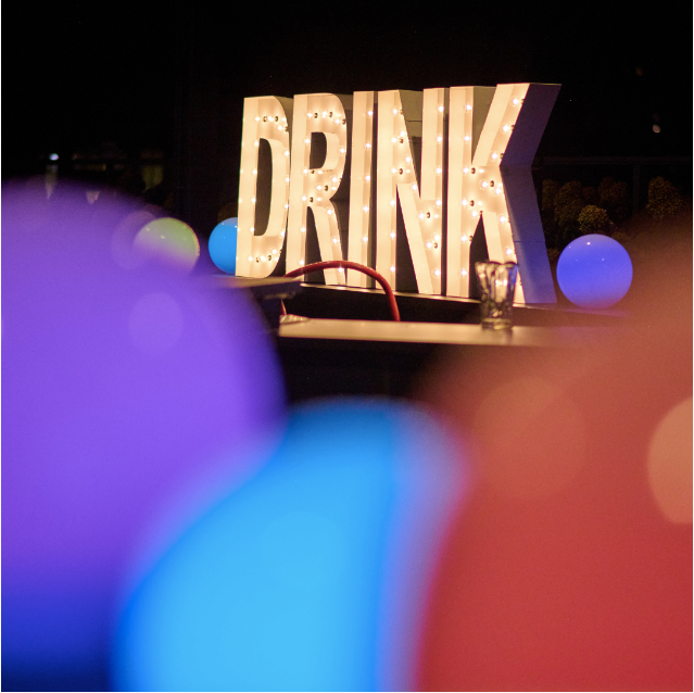 A drink sign is lit up in a dark room