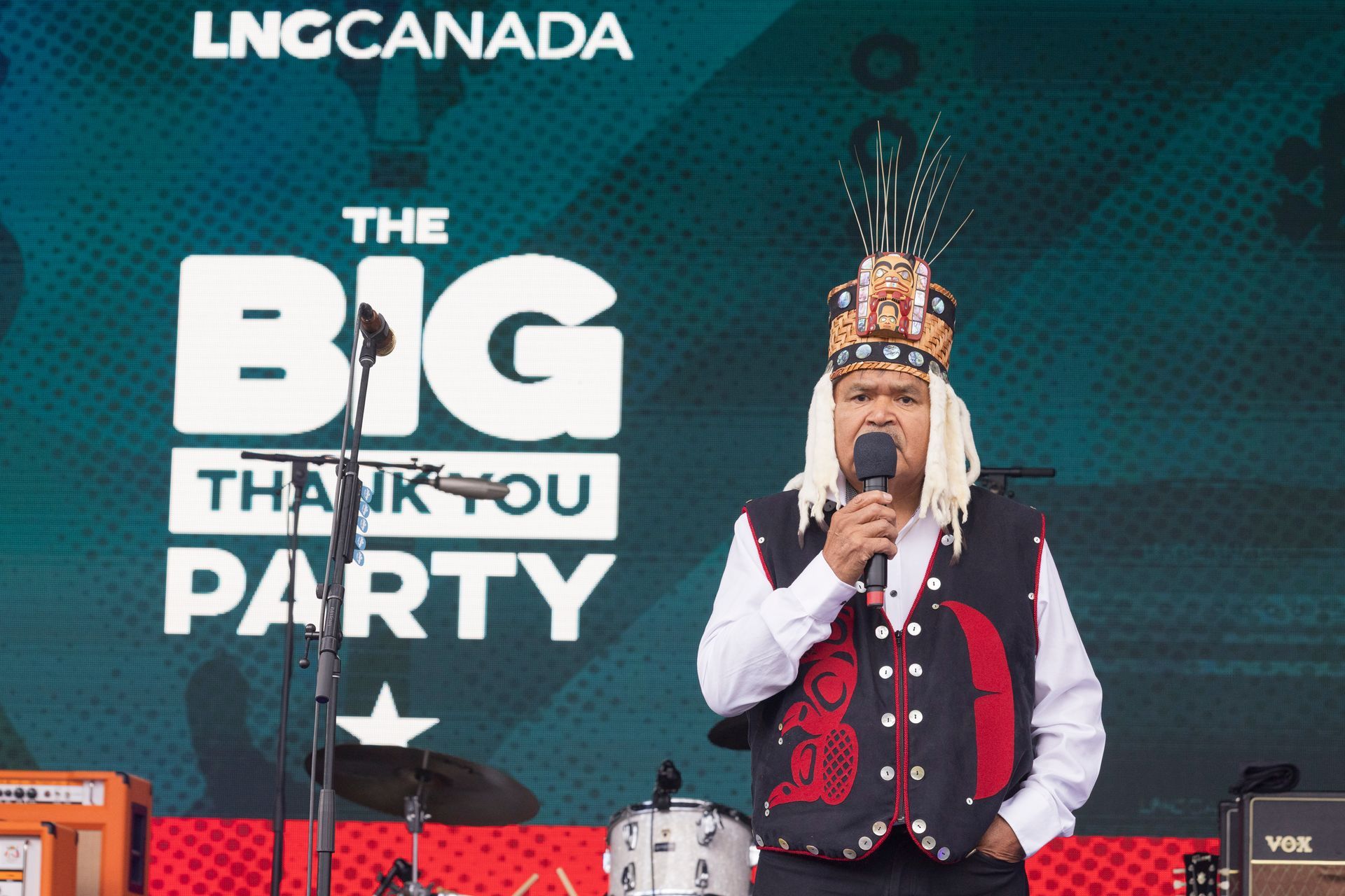 Man in traditional regalia speaks at a 