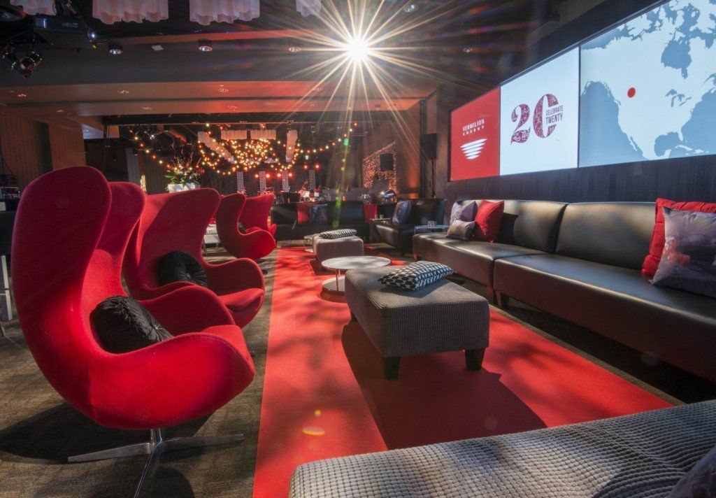 A living room with red chairs and a large screen that says 20