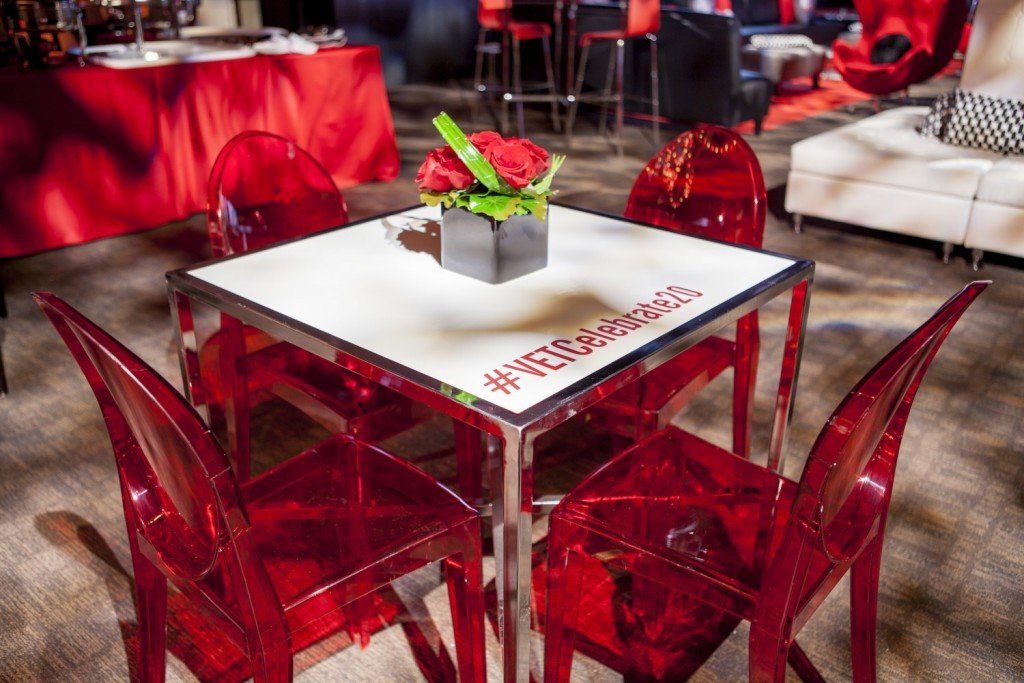 A table with red chairs and a vase of flowers on it