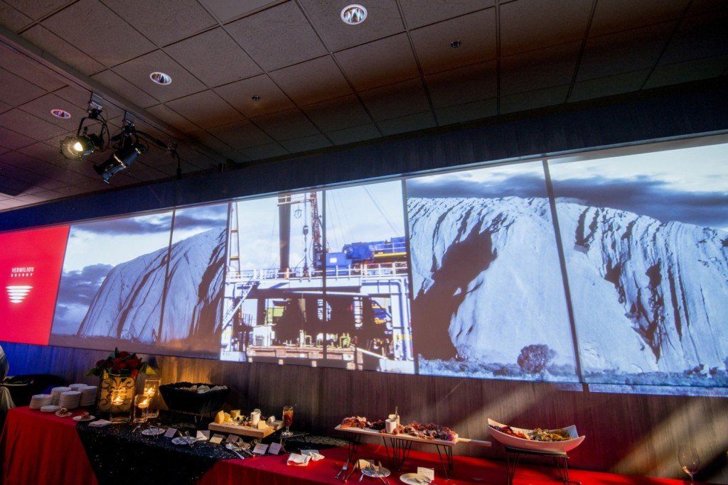 A large screen is projected on a wall behind a buffet table.