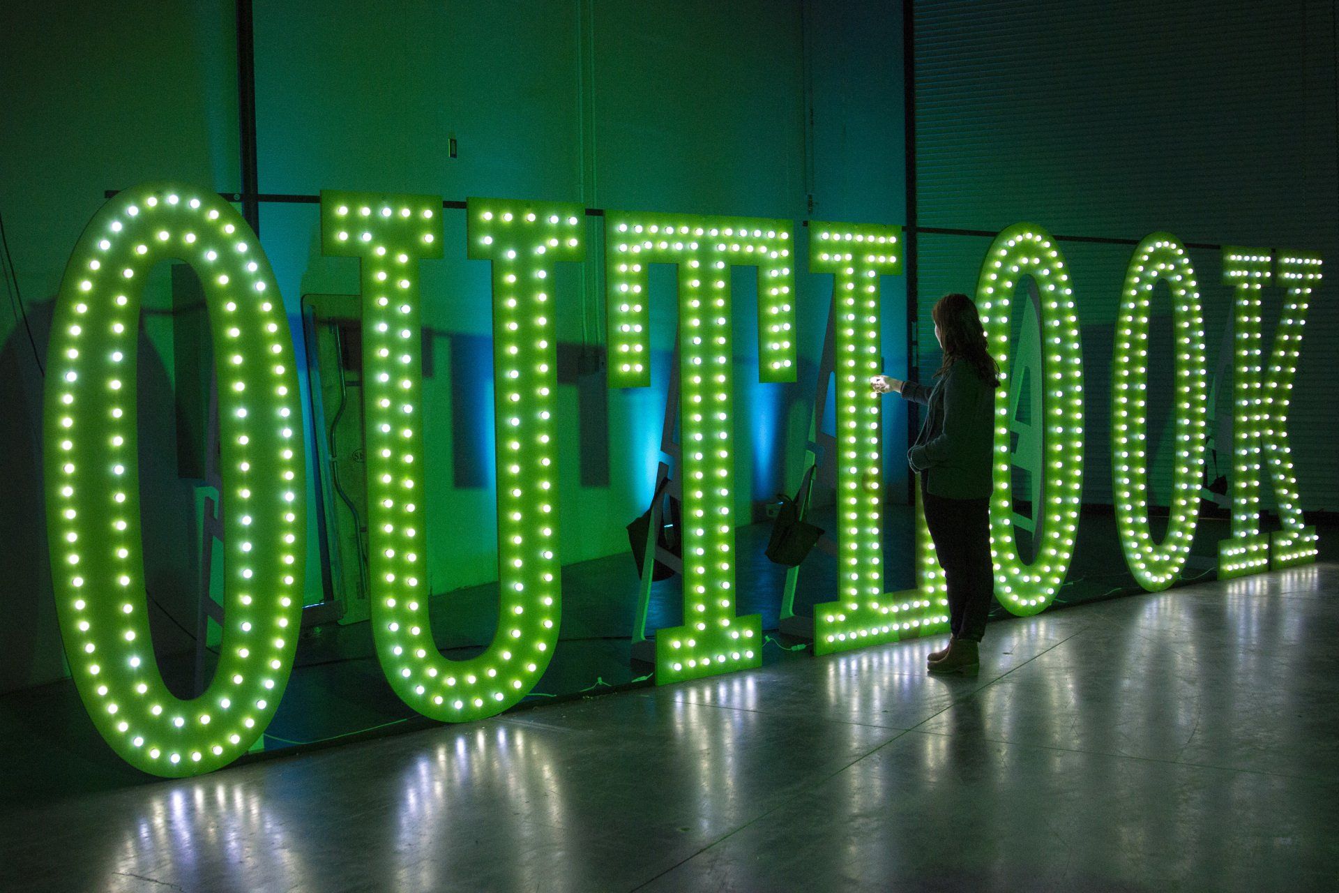 A person is standing in front of a sign that says outlook