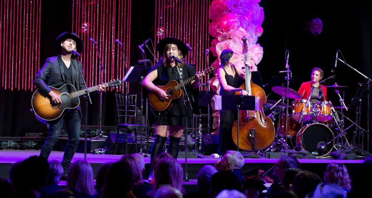 A group of people are playing instruments on a stage in front of a crowd.