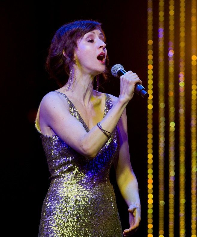 A woman in a sequined dress is singing into a microphone