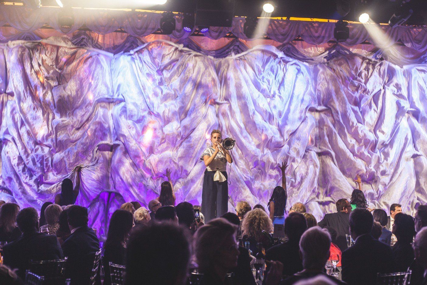 A man is standing on a stage in front of a crowd of people.