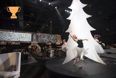 A woman is dancing in front of a large christmas tree
