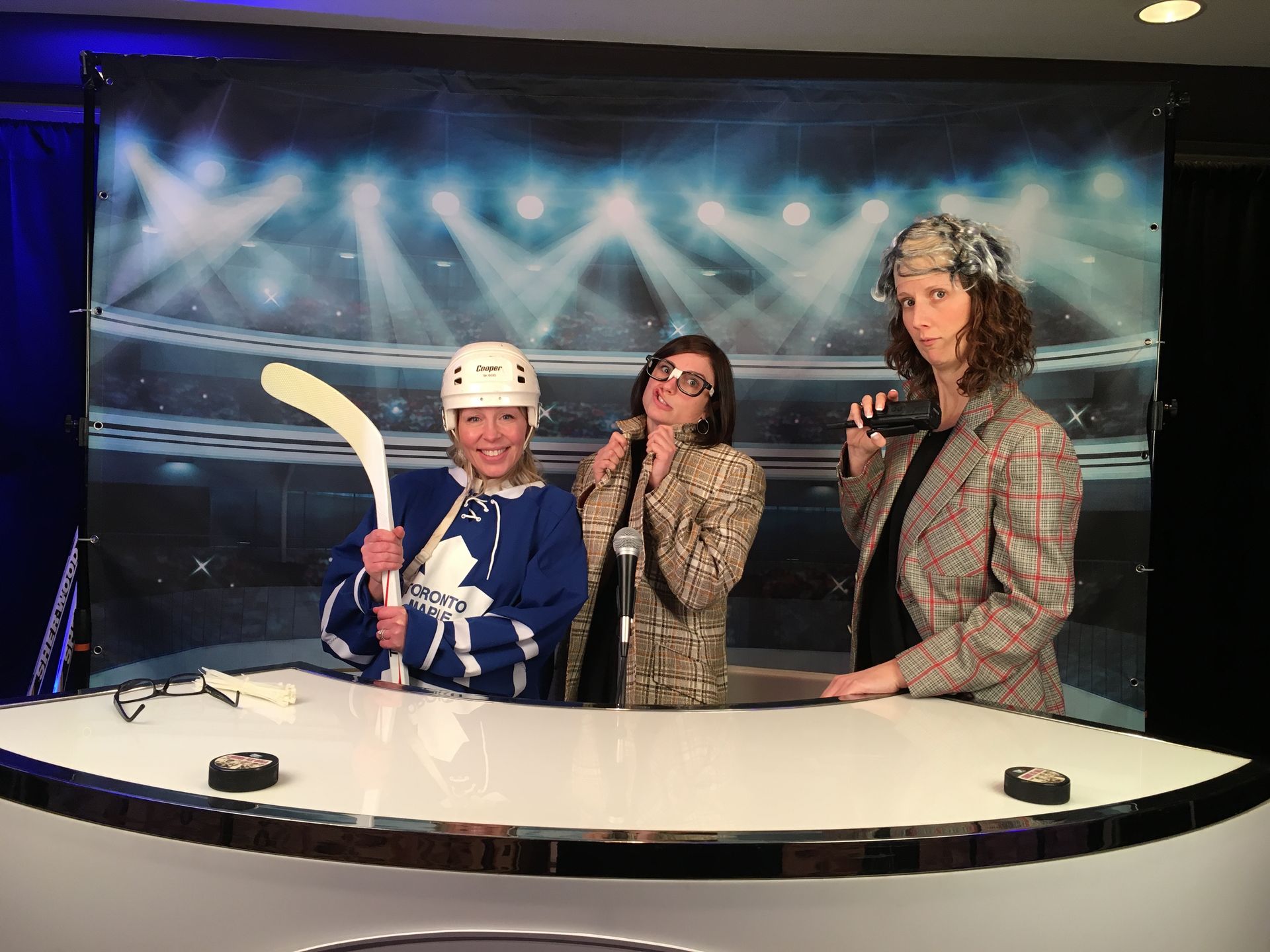 Three people are posing for a picture in front of a hockey rink.