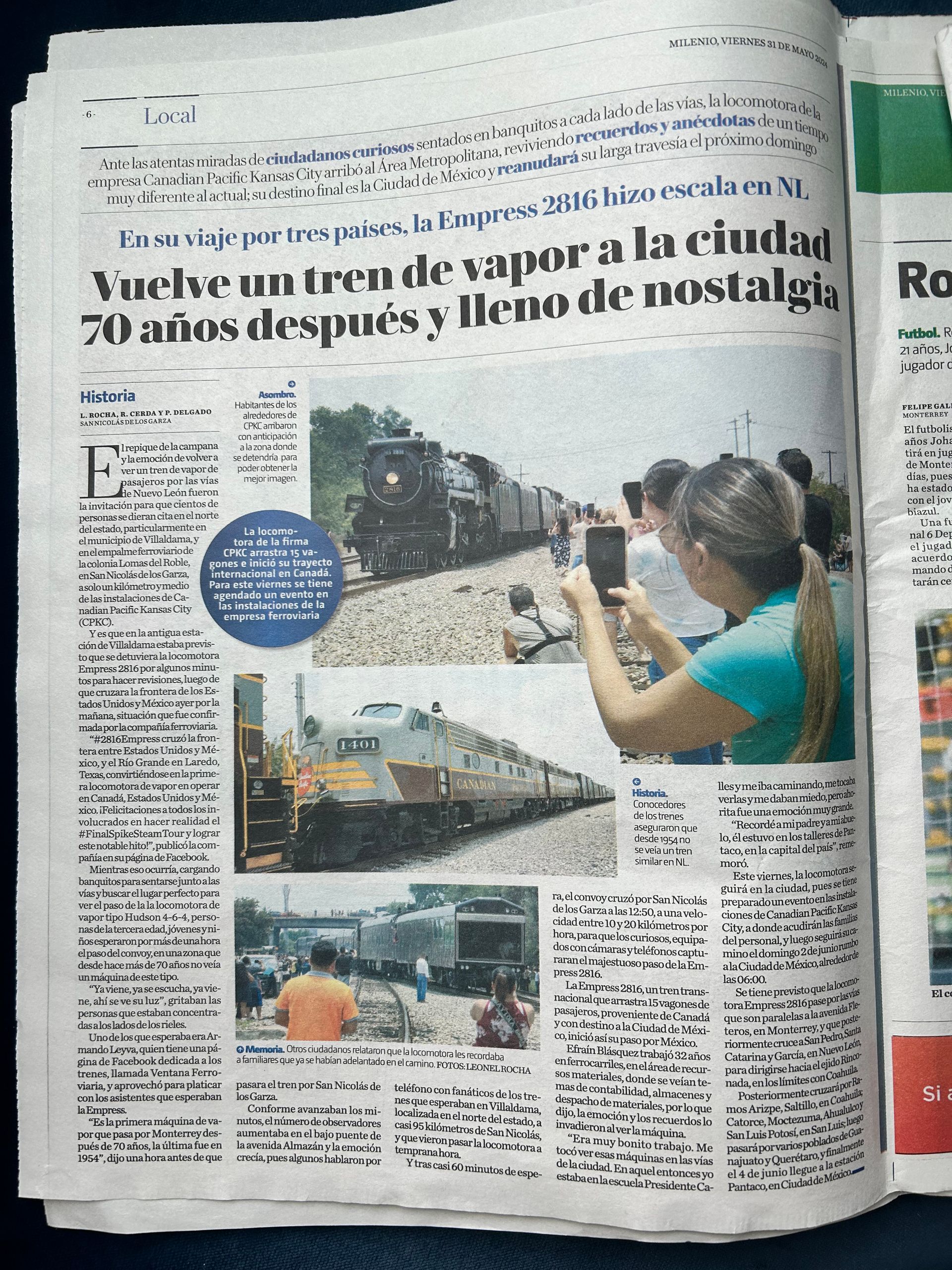 A woman is taking a picture of a train in a newspaper