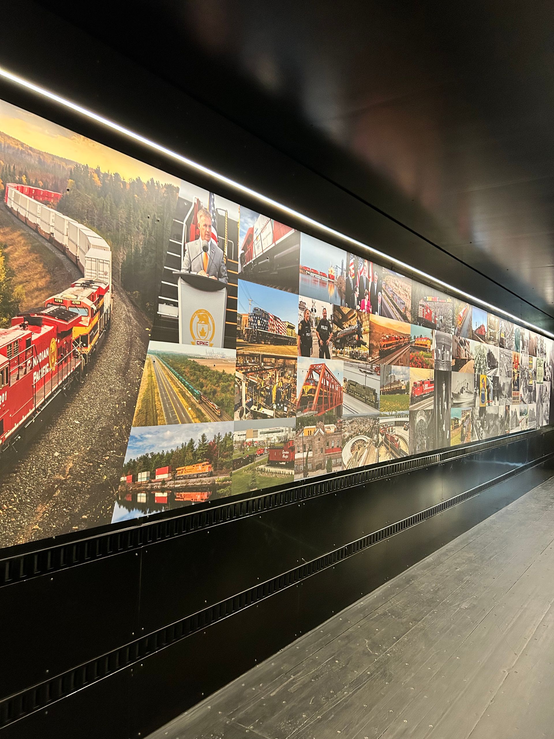 A long hallway with a painting of a train on the wall.
